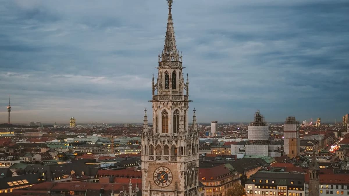 Transferhood — Munich: Your Gateway to Bavaria and the Alps (the Gothic tower of the New Town Hall over the old city at dusk)